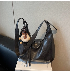 Close-up of black vintage leather tote bag with cute plush keychain charm detail