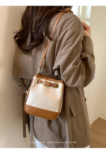 Detail of minimalist two-tone crossbody bag with leather strap and buckle accent