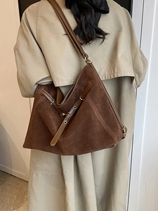 Large dark brown suede hobo bag worn by a model in a beige trench coat for a casual autumn look
