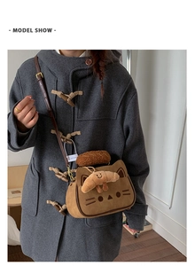 Détail d'un sac bandoulière chat marron avec pendentif croissant en peluche sur manteau