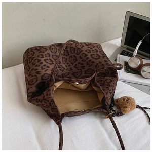 Detail view of leopard print tote bag with magnetic closure and bear charm accessory