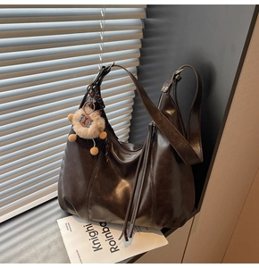 Detail of vintage dark brown faux leather tote bag with a cute plush animal keychain