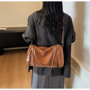 Dettaglio di una borsa Boston marrone retrò indossata da una modella in studio