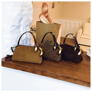 Detail view of retro barrel bags with vintage gold chain hardware and leopard print finish