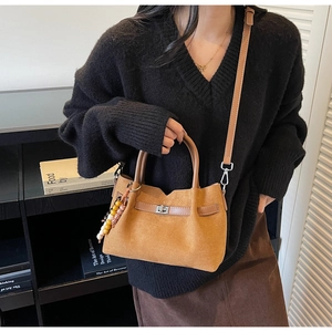 Détail d'un sac seau en daim marron avec boucle métallique et breloque en perles colorées