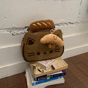 Détail d'un sac chat en daim marron avec broderie et breloque en forme de croissant