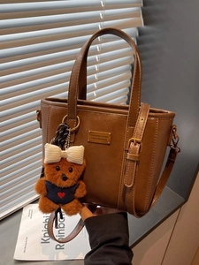 Vintage dark brown bucket bag with gold logo plaque and cute teddy bear charm