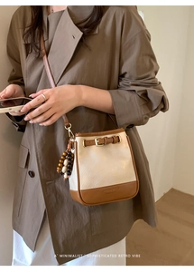 Detail of vintage color-block crossbody bucket bag with beige and brown leather stitching
