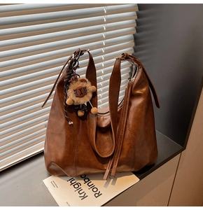 Close-up of large brown faux leather tote bag featuring a cute plush animal pendant