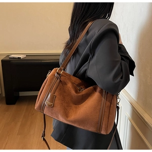 Close-up of caramel matte suede shoulder bag featuring dual straps and retro texture