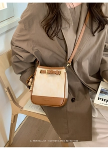 Detail view of contrast canvas bucket bag with brown leather trim and wooden bead charm