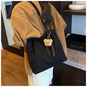 Detail of black large-capacity tote bag with bear charm and striped ribbon accent