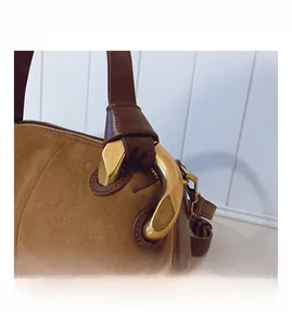 Macro detail of brown suede tote bag with golden metal ring and smooth leather handle