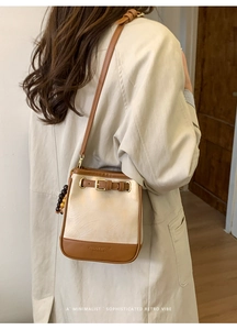Detail shot of a minimalist two-tone crossbody bag with elegant bead decor and gold buckle