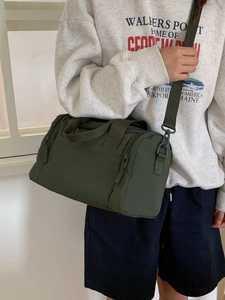 Borsa a tracolla cilindrica in tela verde oliva indossata da una modella casual