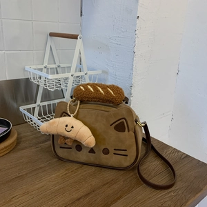 Détail d'un sac à main chat marron avec poignée en peluche et pendentif croissant sur bois