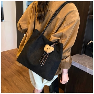 Close-up of a large black vintage tote bag with a brown plush bear charm detail