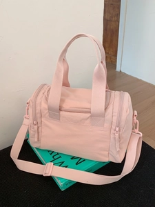 Borsa fitness in nylon rosa con doppi manici e tracolla regolabile su un libro