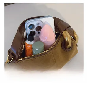 Detail showing internal capacity of brown suede pillow bag with phone and cosmetics