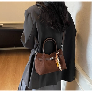 Détail du sac seau en daim marron avec fermoir métallique et perles de bois colorées