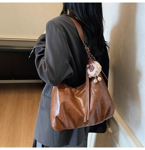 Detail einer dunkelbraunen Vintage-Hobo-Tasche aus Leder mit Plüsch-Anhänger