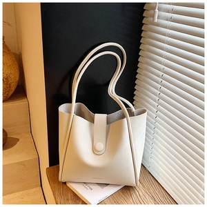 Detail of off-white lychee leather tote bag with ROCOMI logo and snap strap closure