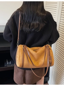 Borsa Boston in camoscio marrone con cinturini in pelle in un ambiente minimalista