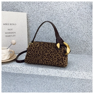 Detail of leopard print cylinder bag with brown leather handle and gold chain buckle