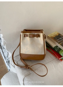 Close-up of a minimalist bucket bag featuring contrast leather trim and logo embossing