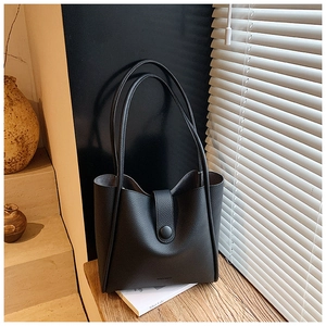 Detail view of the black lychee grain leather tote bag with elegant buckle and handle straps
