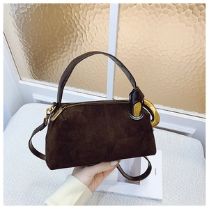 Macro detail of dark brown suede handbag featuring luxury gold hardware and ring