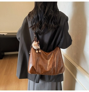 Detail of vintage caramel brown hobo bag with plush charm and printed silk scarf