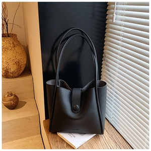 Close-up of black lychee-grain leather tote bag with magnetic clasp and logo detail