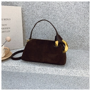 Detail of dark brown suede handbag featuring a bold gold polygonal metallic buckle