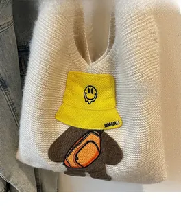 Detailed view of the white knitted tote bag featuring a cute cartoon bear embroidery patch