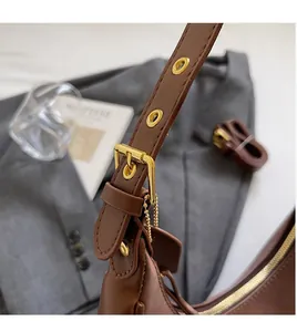 Detail of adjustable dark brown leather shoulder strap with gold metal eyelets and buckle