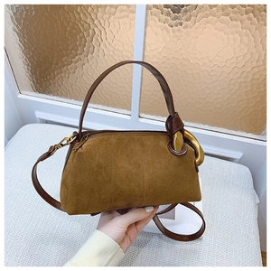 Detail view of brown suede pillow bag with golden metal buckle and zipper top