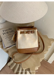 Close-up of contrast bucket bag featuring embossed leather logo and wood bead charm
