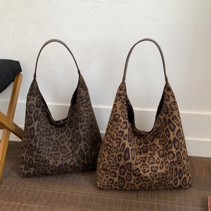 Detail of leopard print tote bags in dark and light brown tones with leather straps