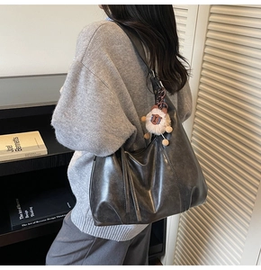 Detail of grey shoulder bag with soft gloss material and cute white sheep charm
