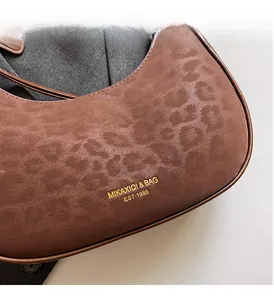 Close-up of brown leopard print crescent bag with suede texture and gold logo details