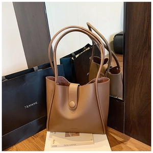 Detail of brown litchi pattern leather tote bag with magnetic snap and slim shoulder straps