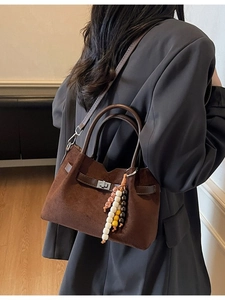Sac seau en daim marron foncé avec fermoir en métal et perles sur blazer gris foncé