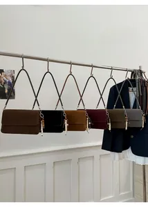 Minimalist faux suede underarm bags in various colors with bead charms on a display rack