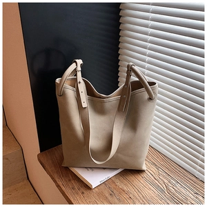 Detail einer großen beigen Shopper-Tasche mit matter Wildleder-Optik auf Holzfläche