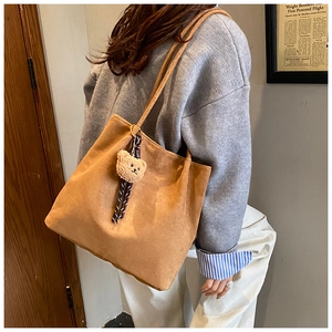 Detail of vintage brown tote bag with bear charm pendant and shoulder strap design