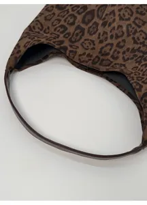 Close-up of comfortable dark leather handle and leopard print fabric on tote bag
