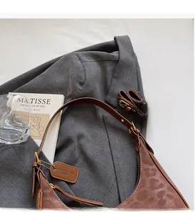 Detail of hobo bag with leopard texture on grey suit and decorative Matisse books