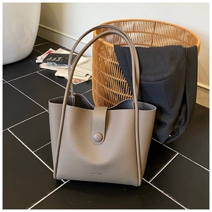 Detail of taupe lychee leather tote bag with magnetic snap and HOCOMO branding