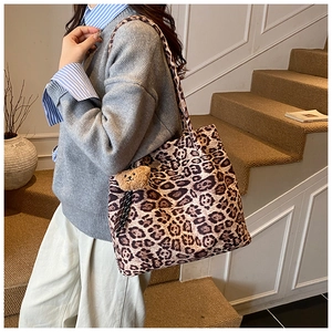 Detailed view of leopard print tote bag with brown bear charm on casual street style outfit
